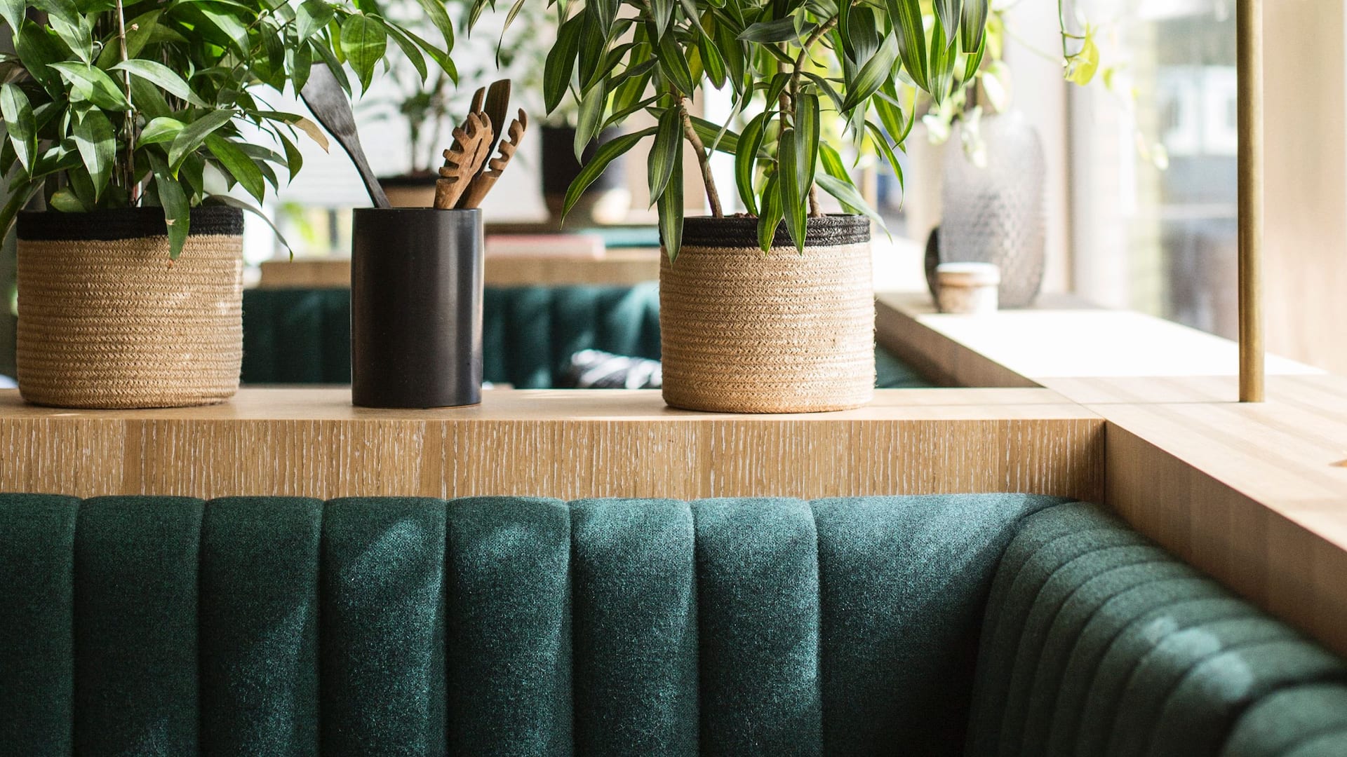A close-up of a seating area at restaurant Mama makan with green booths and plants in woven baskets