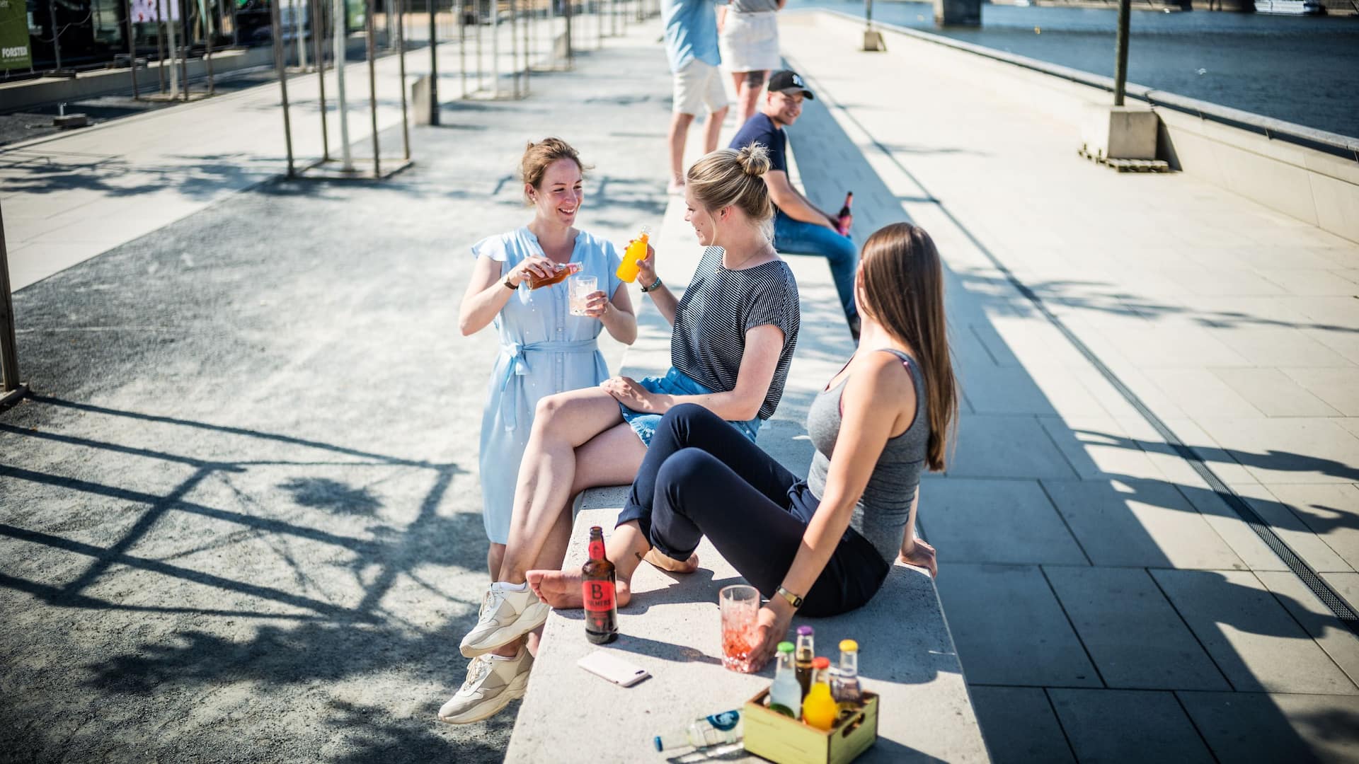 Group of people enjoying drinks on the Rhine promenade in summer in front of Hyatt Regency Cologne