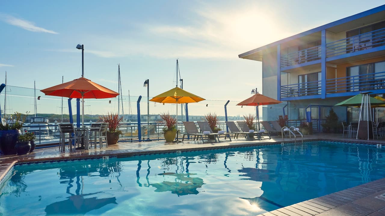 Outdoor pool deck with sun umbrellas and view of the bay
