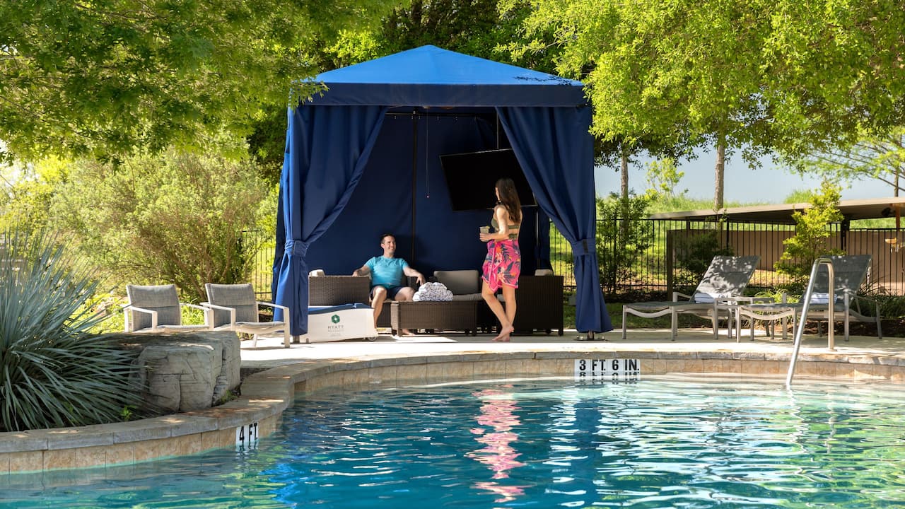 Outdoor pool area with people relaxing in a cabana