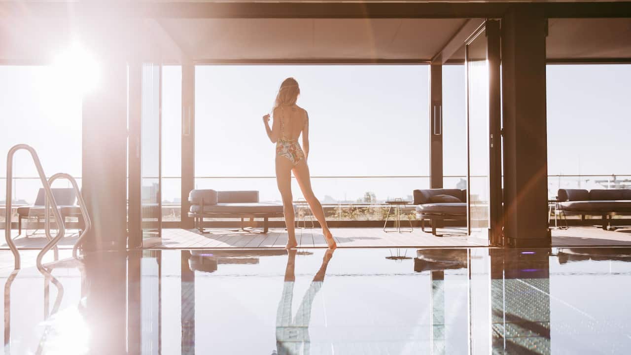 Woman standing next to pool at Andaz Rooftop Spa Munich