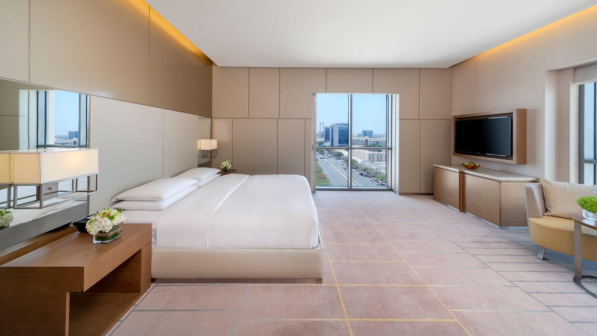 A spacious suite with a king bed, natural lighting and view of city skyline.