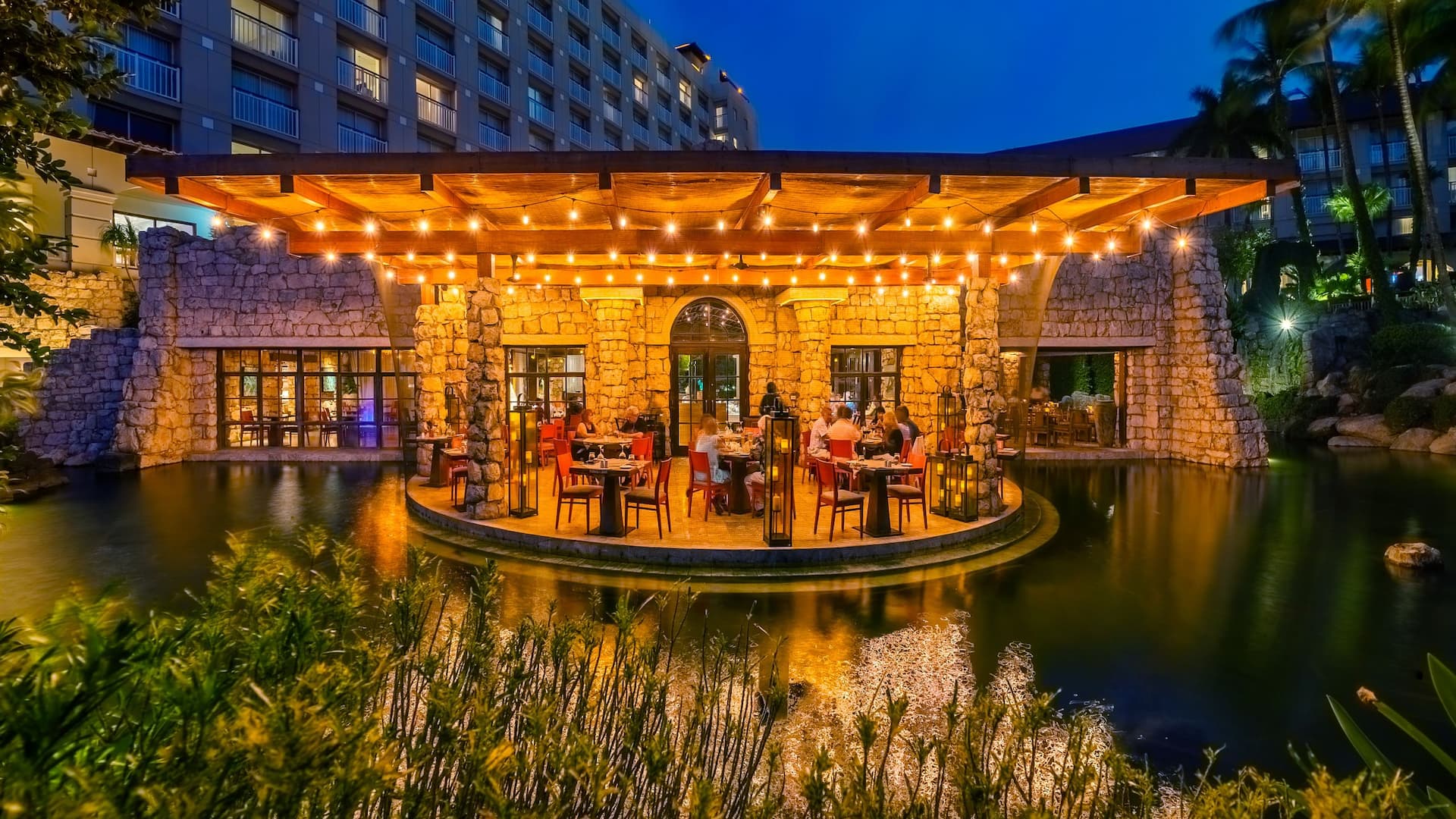 Hotel guests dining at a covered outdoor restaurant overlooking koi lagoon