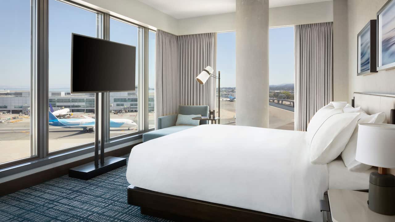 Corner Suite king bed with floor-to-ceiling windows featuring runway views