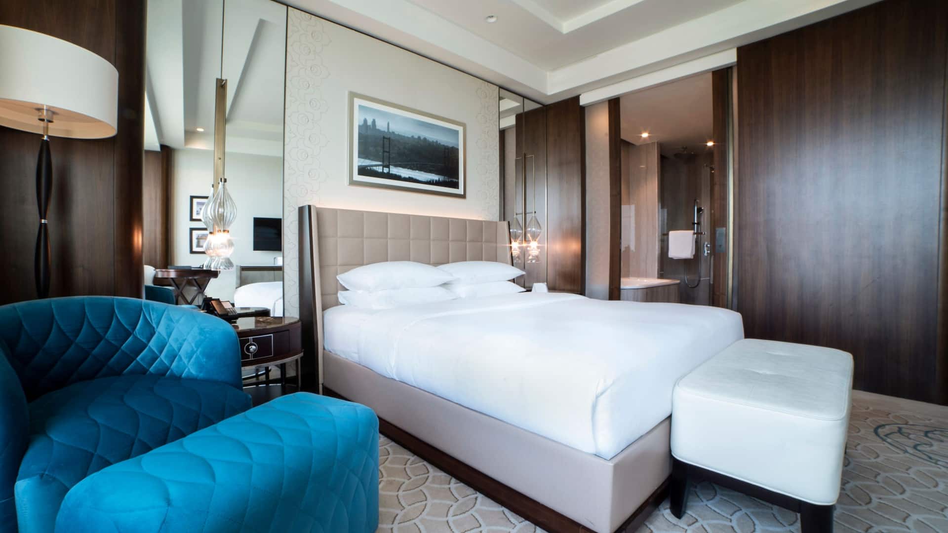 1 King Bed with Club Access at Hyatt Regency Istanbul Ataköy, featuring a tufted beige headboard, plush blue armchair, and modern décor.