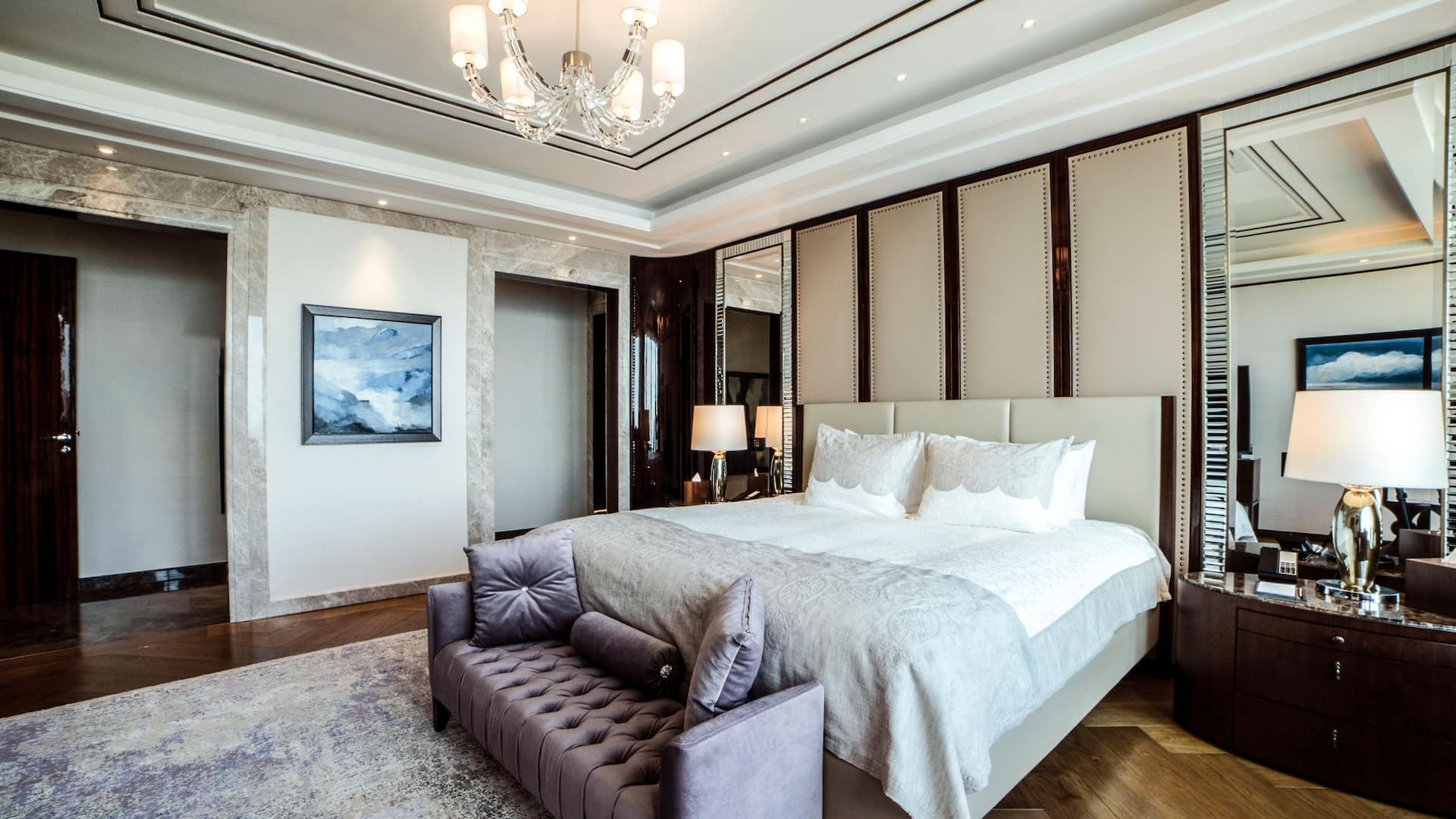 Luxurious Presidential Suite at Hyatt Regency Istanbul Ataköy featuring a plush king-size bed with mirrored accents, an elegant tufted bench, marble details, and a sparkling chandelier for an opulent ambiance.
