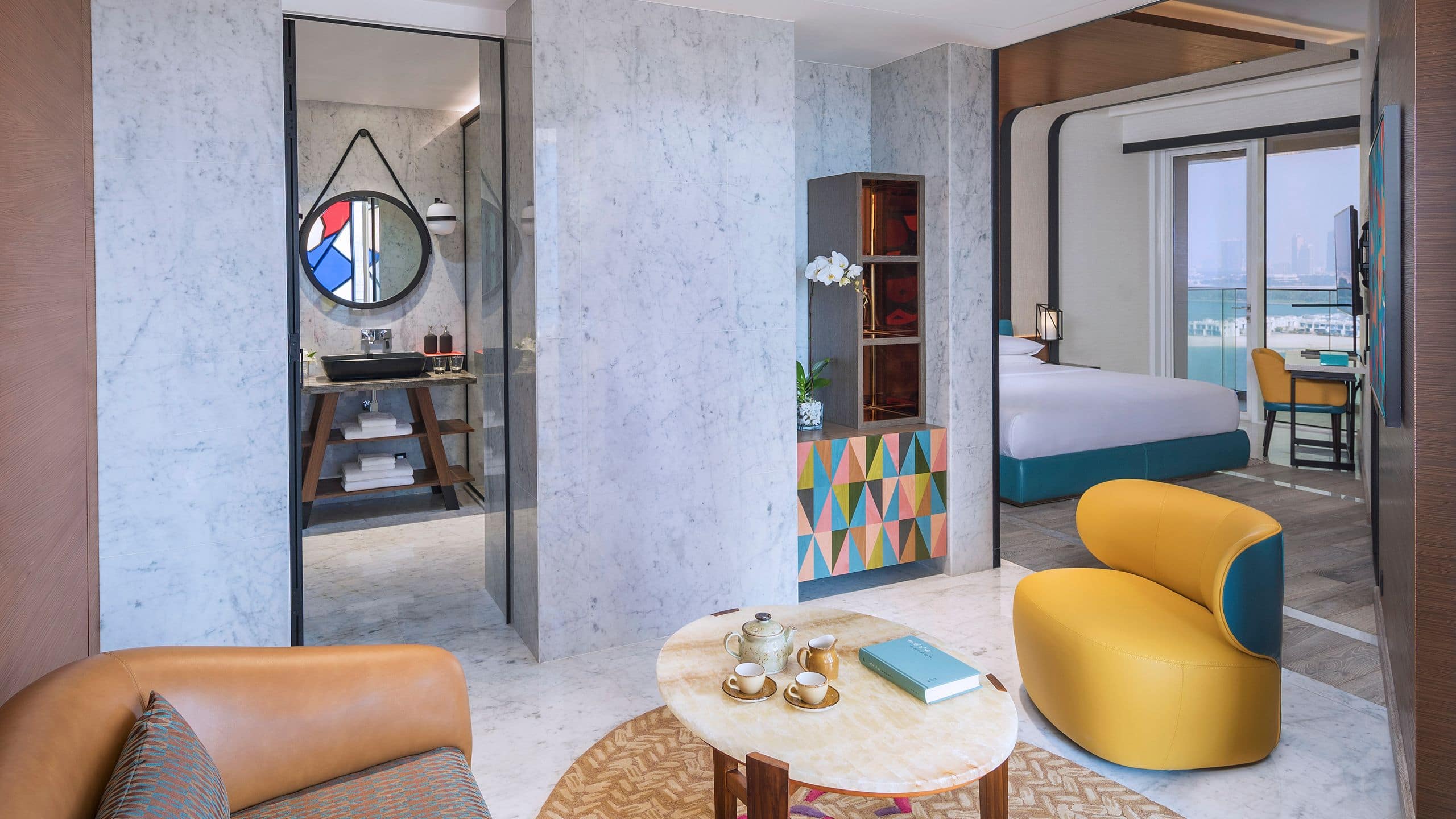 A spacious guestroom with king bed, and stylish living room and bathroom at Andaz Dubai The Palm.
