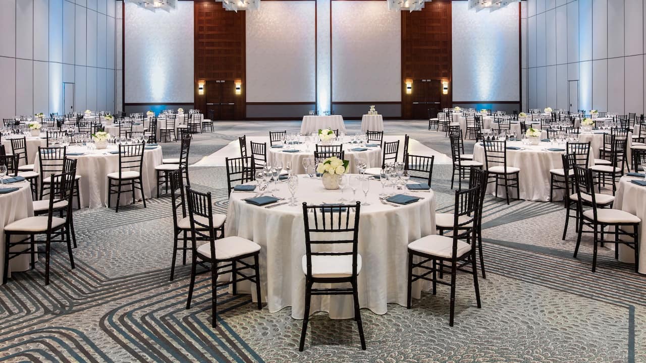 A spacious indoor wedding venue with white themed seating and tables at Indian Wells
