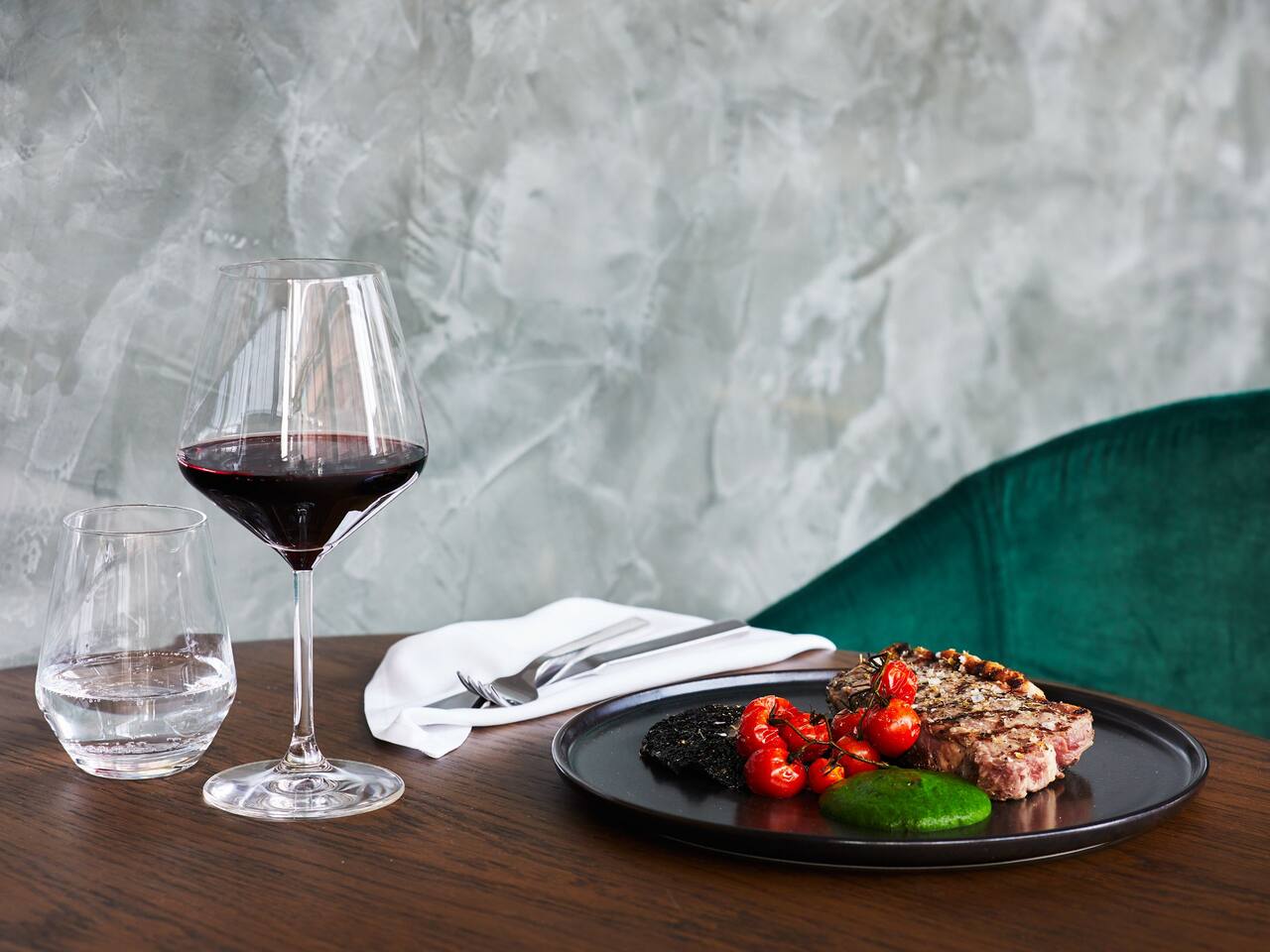 Glass of red wine with steam on a plate against a marble wall 