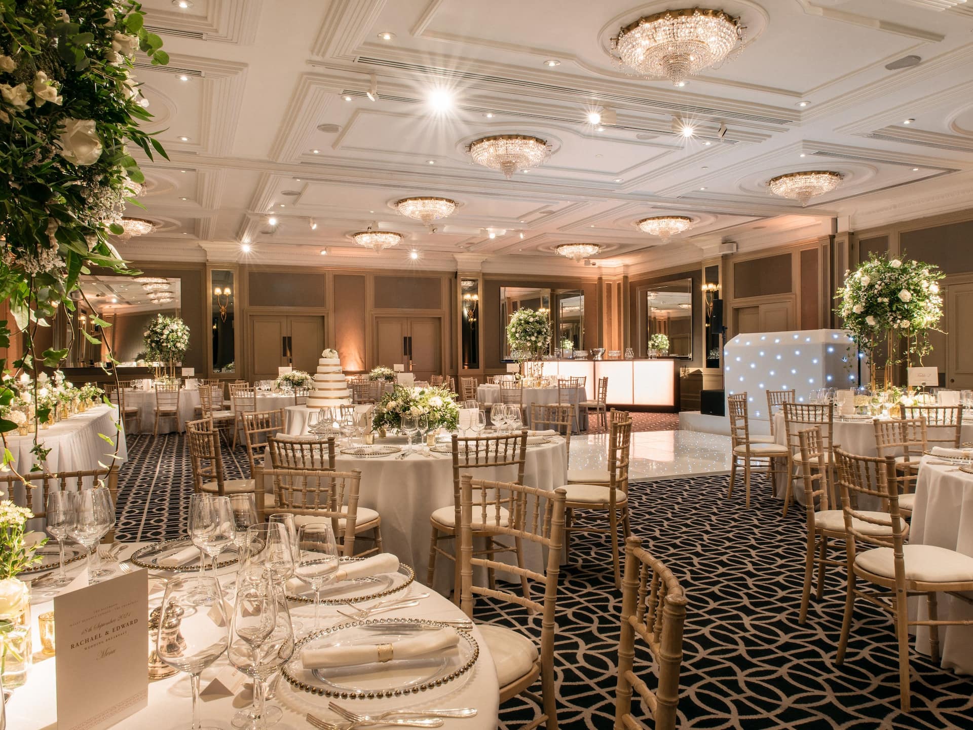 Chartwell Ballroom set up for a wedding with classy and elegant décor, featuring a stage, dancefloor and table centerpieces.