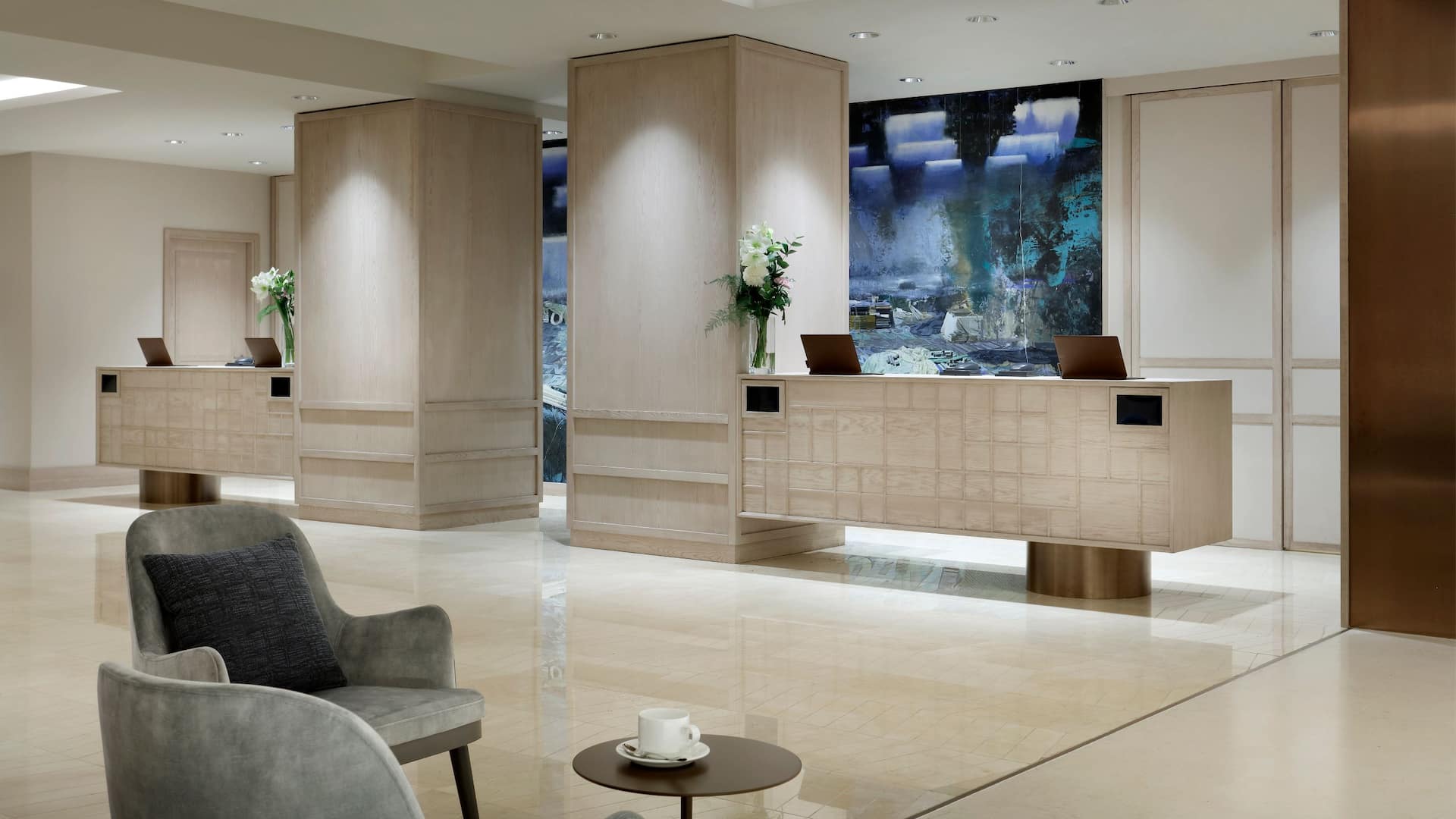 Modern hotel lobby at the Hyatt Regency Hesperia Madrid, designed for an exceptional guest experience with two reception desks and a seating area, situated on Paseo de la Castellana