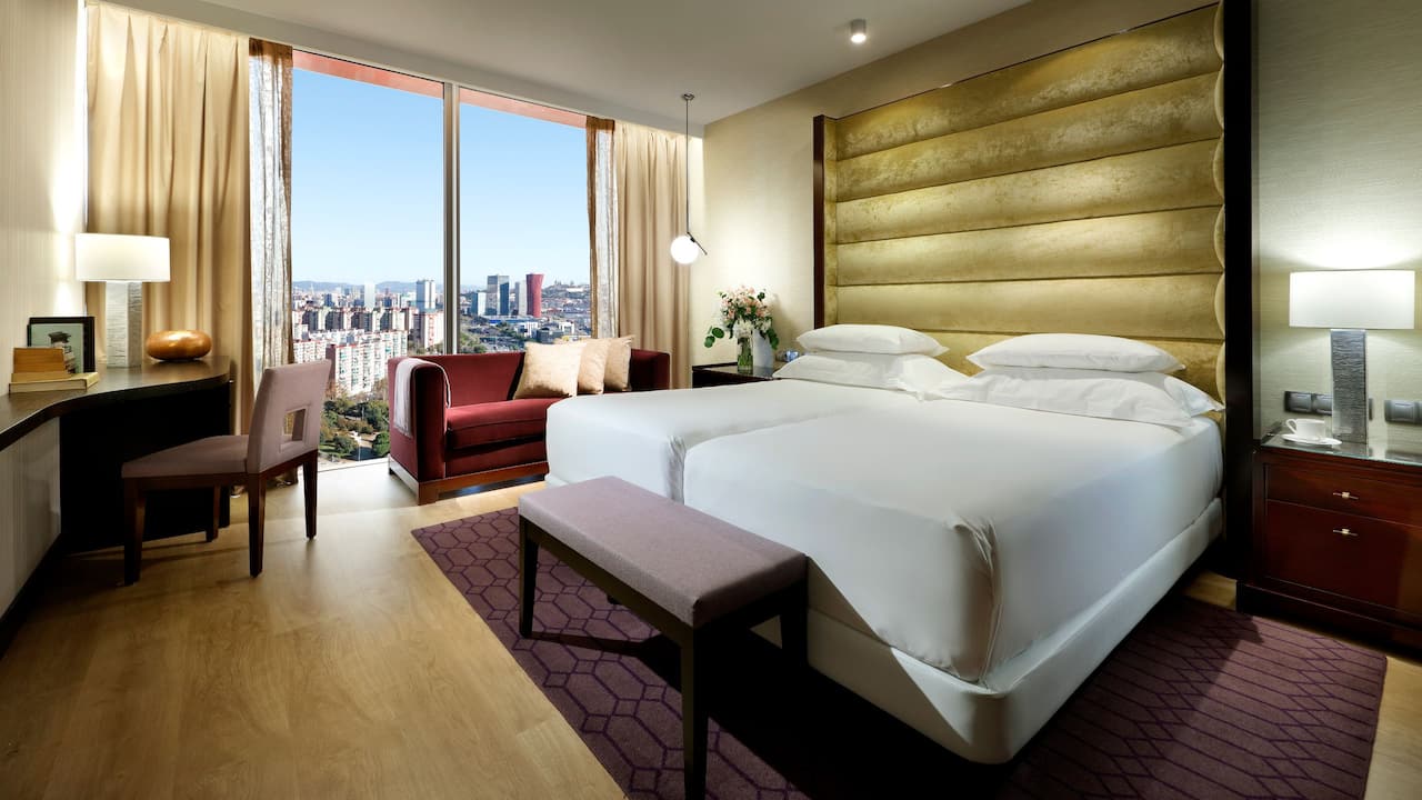 Spacious forty-square-meter Regency Suite Twin Deluxe loft-style room with two beds, located on the top floor of the Hyatt Regency Barcelona Tower hotel and with spectacular views of the city of Barcelona.