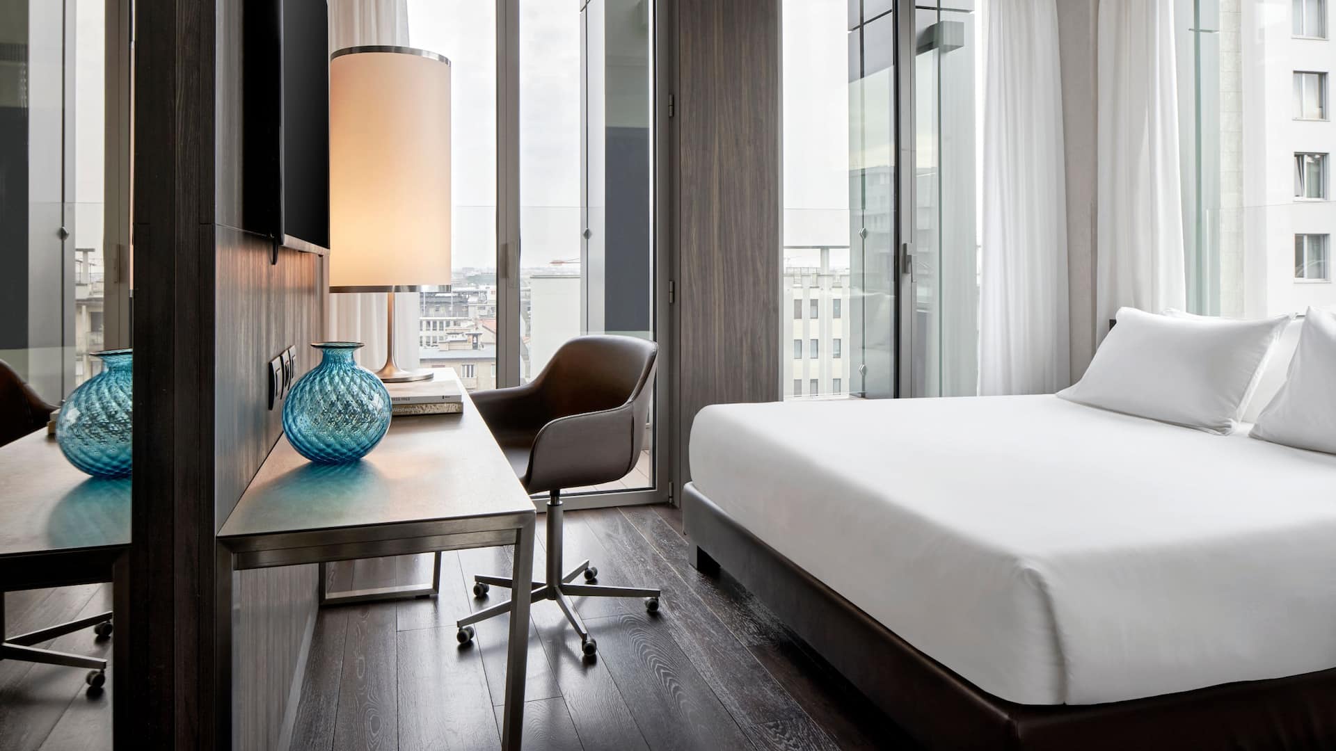 1 of 5 Enjoy floor-to-ceiling windows, a king bed, and a modern bathroom with double sinks and a walk-in shower in the Skyline Suite at design hotel Hyatt Centric Milan Centrale.
