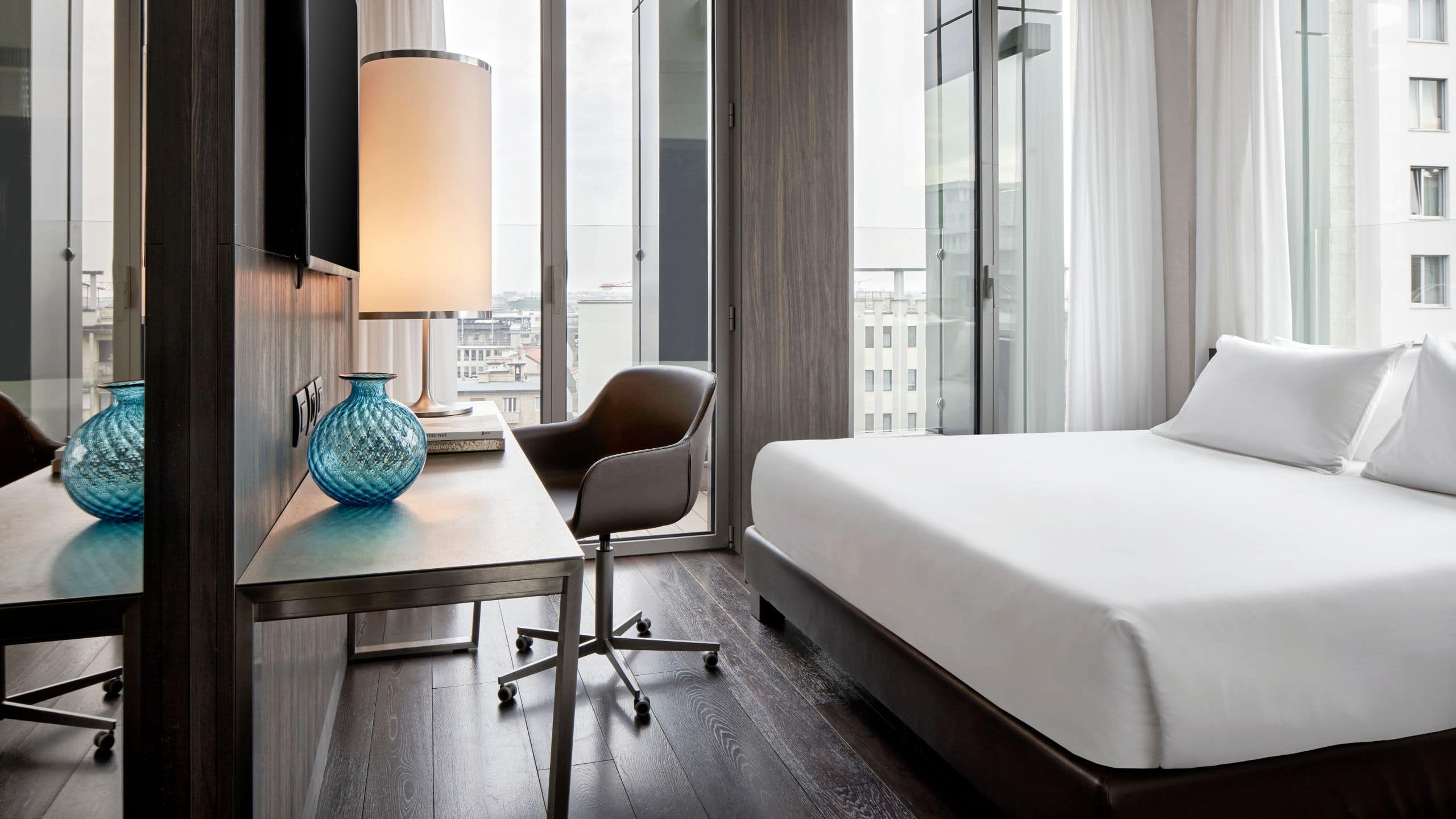 第 1，共 5 Enjoy floor-to-ceiling windows, a king bed, and a modern bathroom with double sinks and a walk-in shower in the Skyline Suite at design hotel Hyatt Centric Milan Centrale.