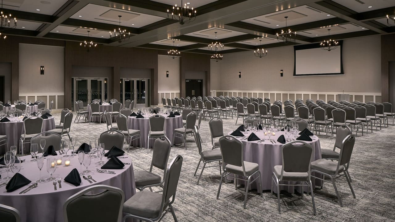 Riverfront Events Ballroom with theater setup, banquet tables and projector screen