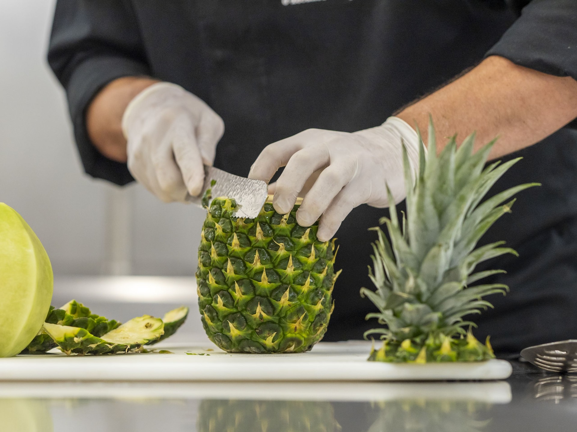 Global GLOBAL_P375 Chef with Gloves PPE Prepares Pineapple