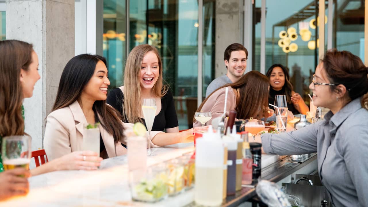 Guests laughing and enjoying cocktails at Kennedy Rooftop Bar