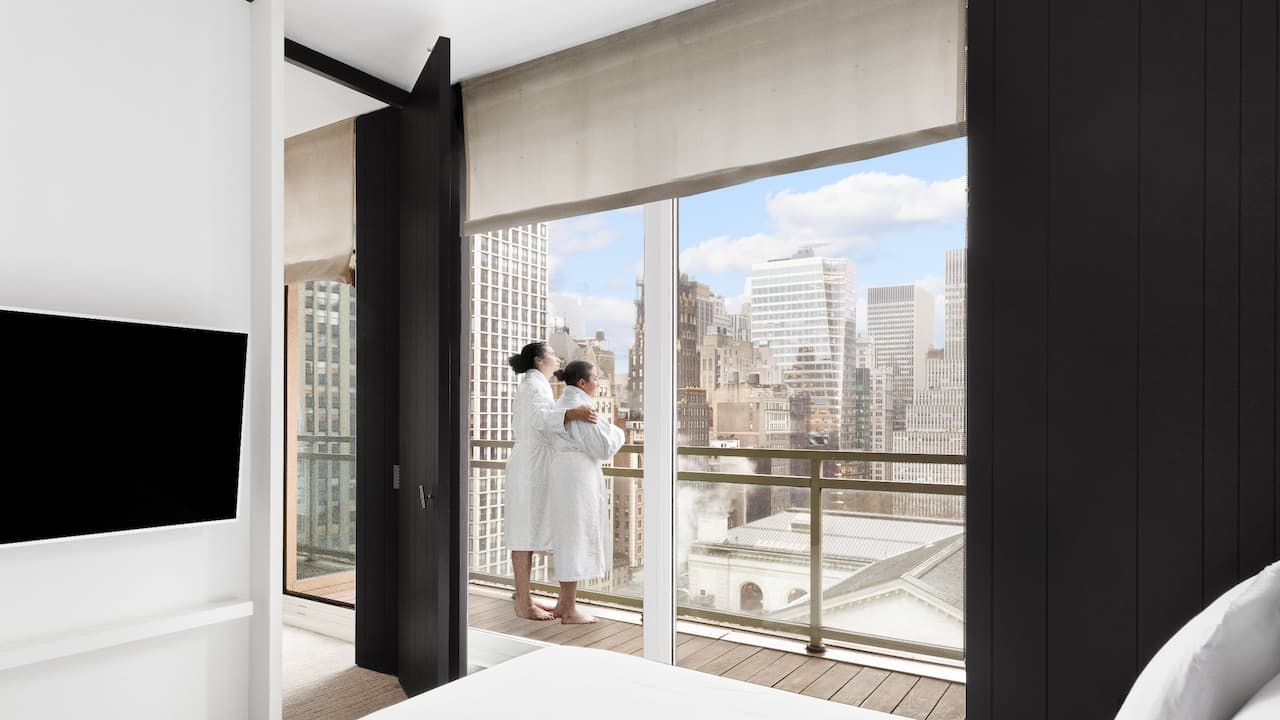 Couple looking at the city from their midtown Manhattan hotel suite