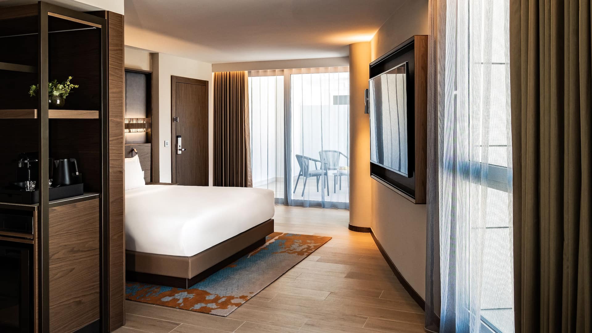 A regency suite with king bed and pjazza view hotel room in the Hyatt Regency Malta with muted blue and earthy colours and the wardrobe