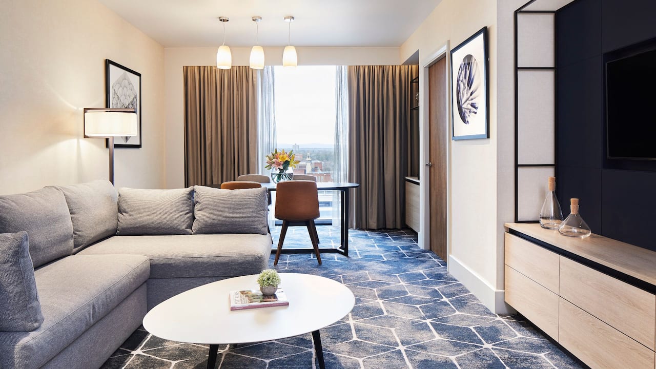 Hotel suite living room area with sofa, TV and dining table