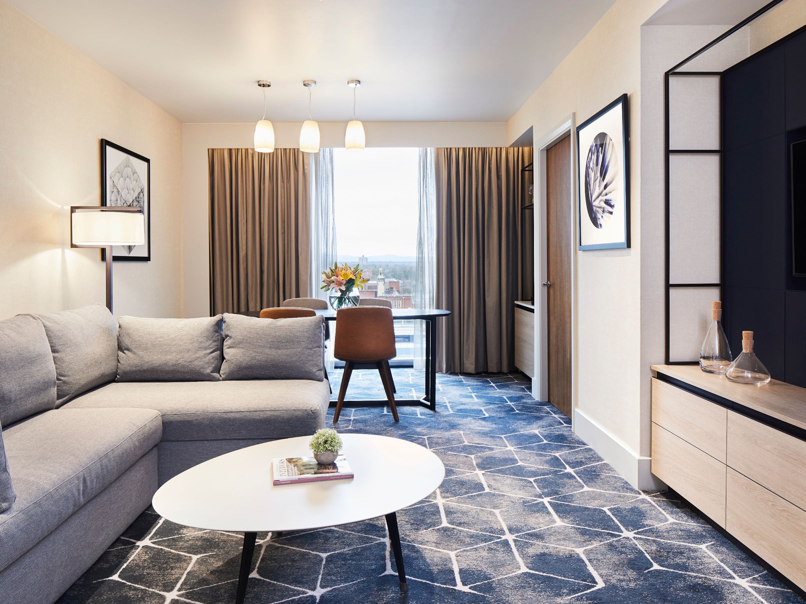 Hotel suite living room area with sofa, TV and dining table