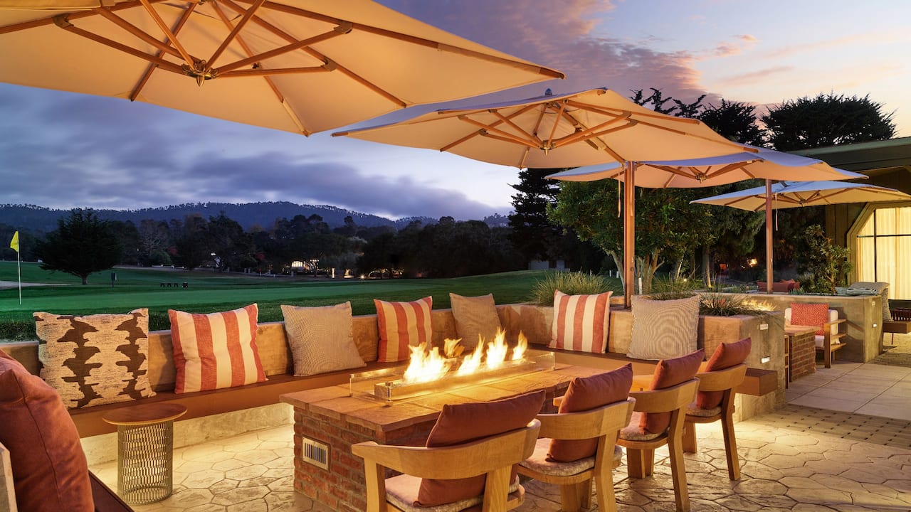 Outdoor seating area with fire pit and view of the golf course at The Bar at Sea Root