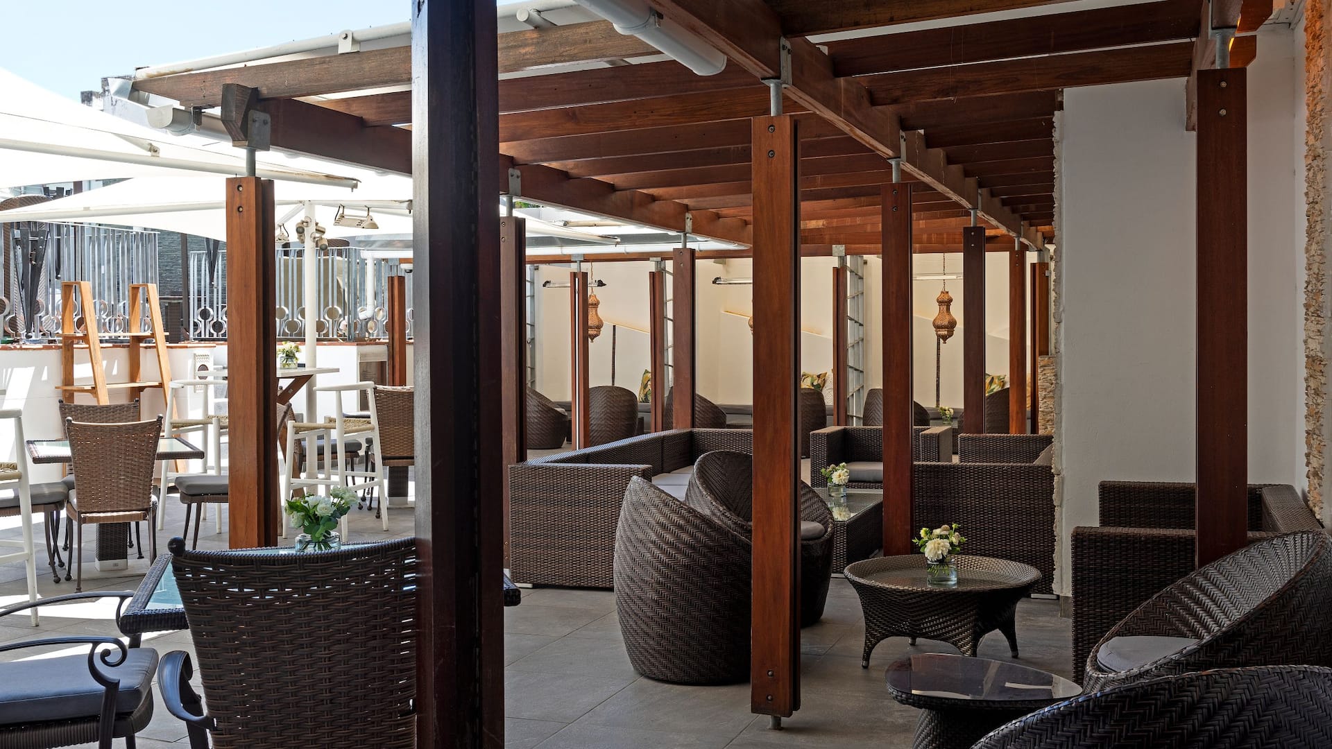 Stylish outdoor lounge area at a luxury Cape Town hotel, featuring wicker furniture, shaded seating, and elegant decor 