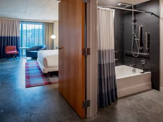Accessible king bed guestroom with tub, looking into bedroom