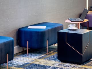 Work area detail with blue ottoman, laptop and cup of coffee