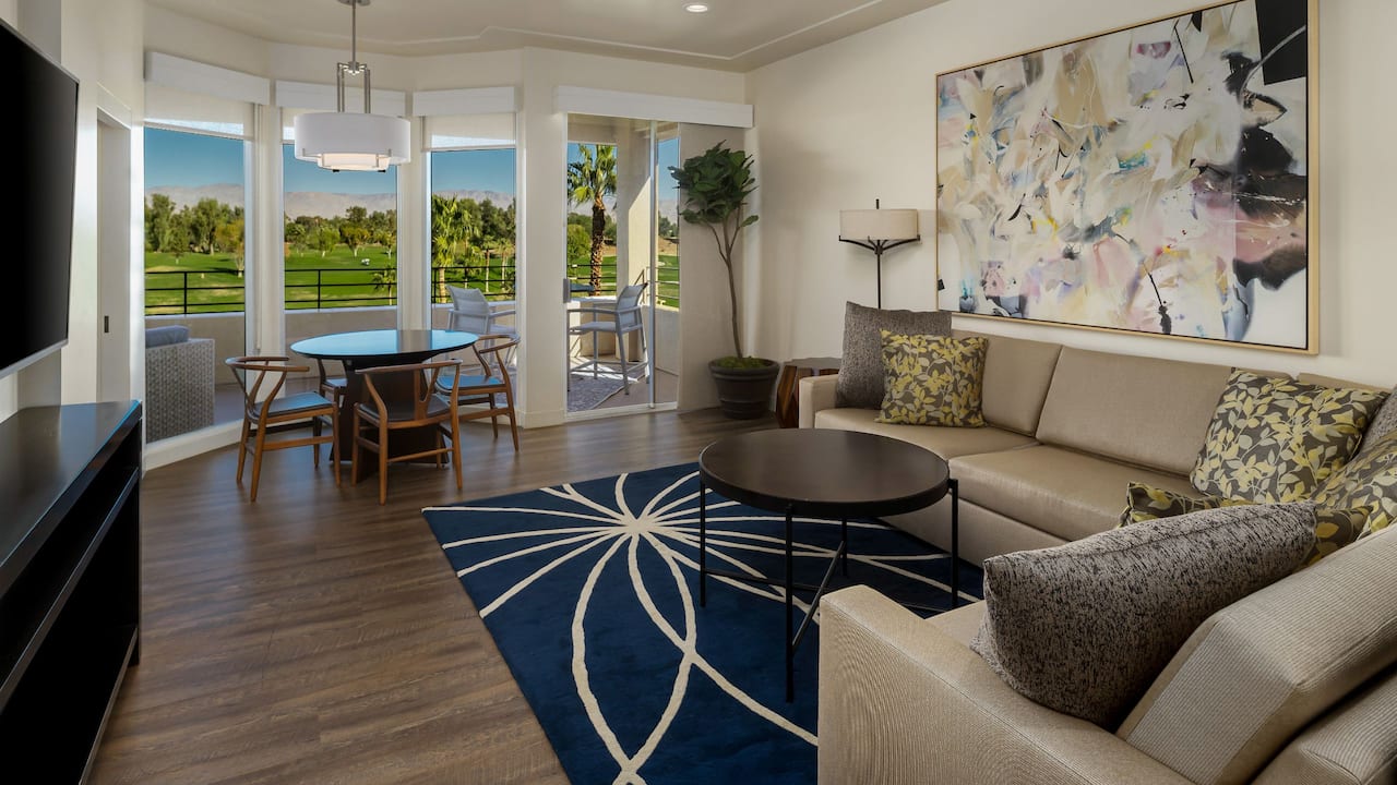 A luxurious penthouse suite with a balcony view overlooking a golf course and mountain views at Indian Wells