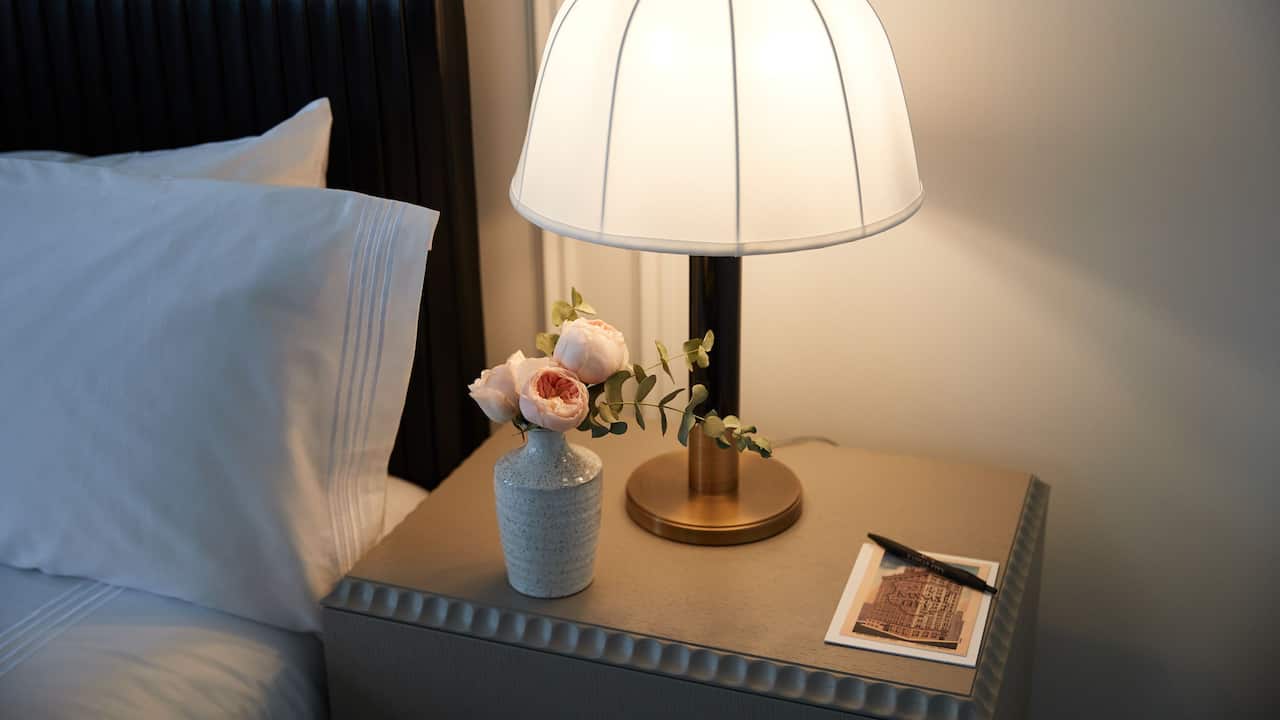 Guestroom nightstand, lamp and a vase of flowers