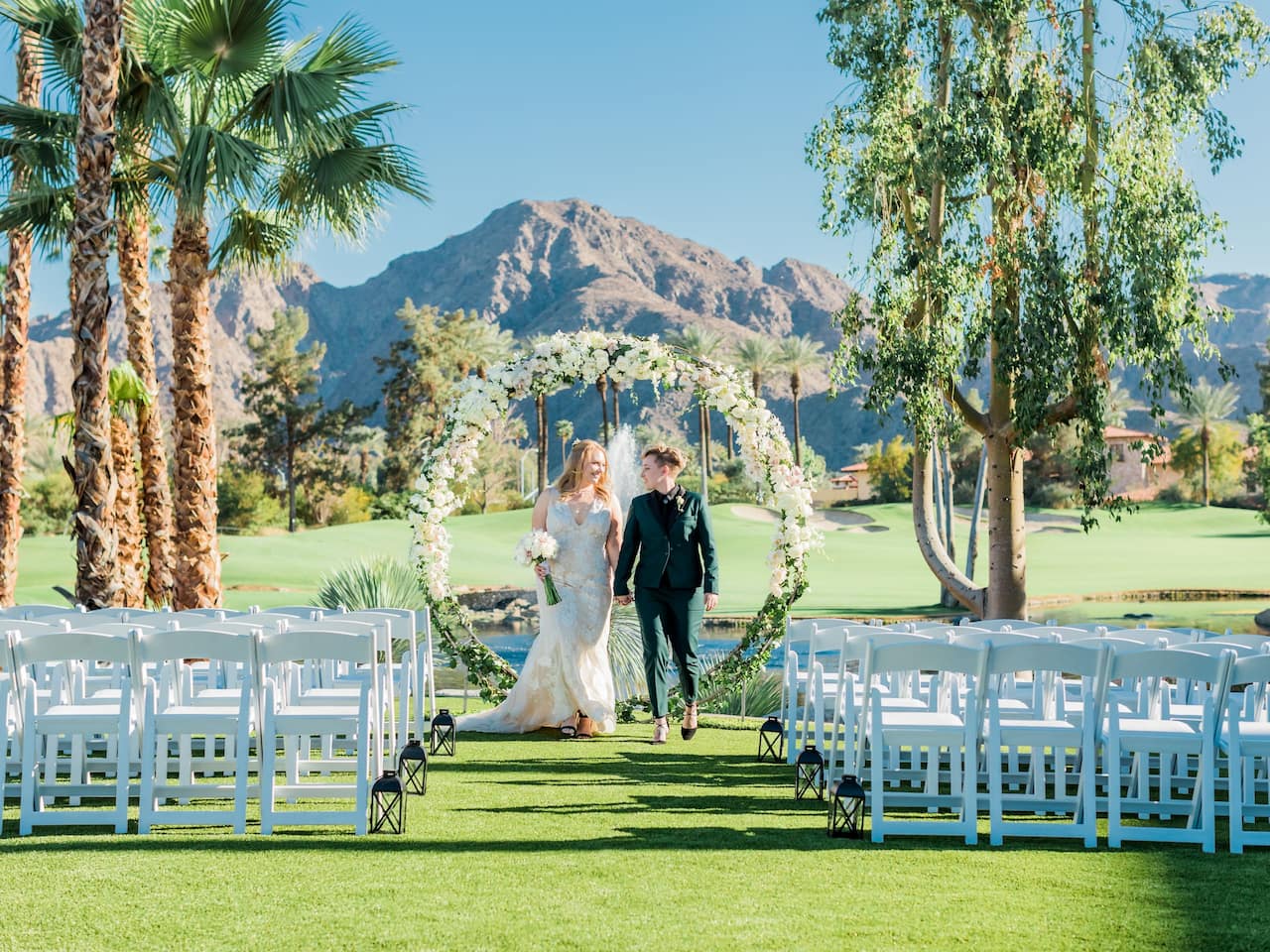 An outdoor wedding reception with white draped tables, flowers, and wine glasses in Palm Springs