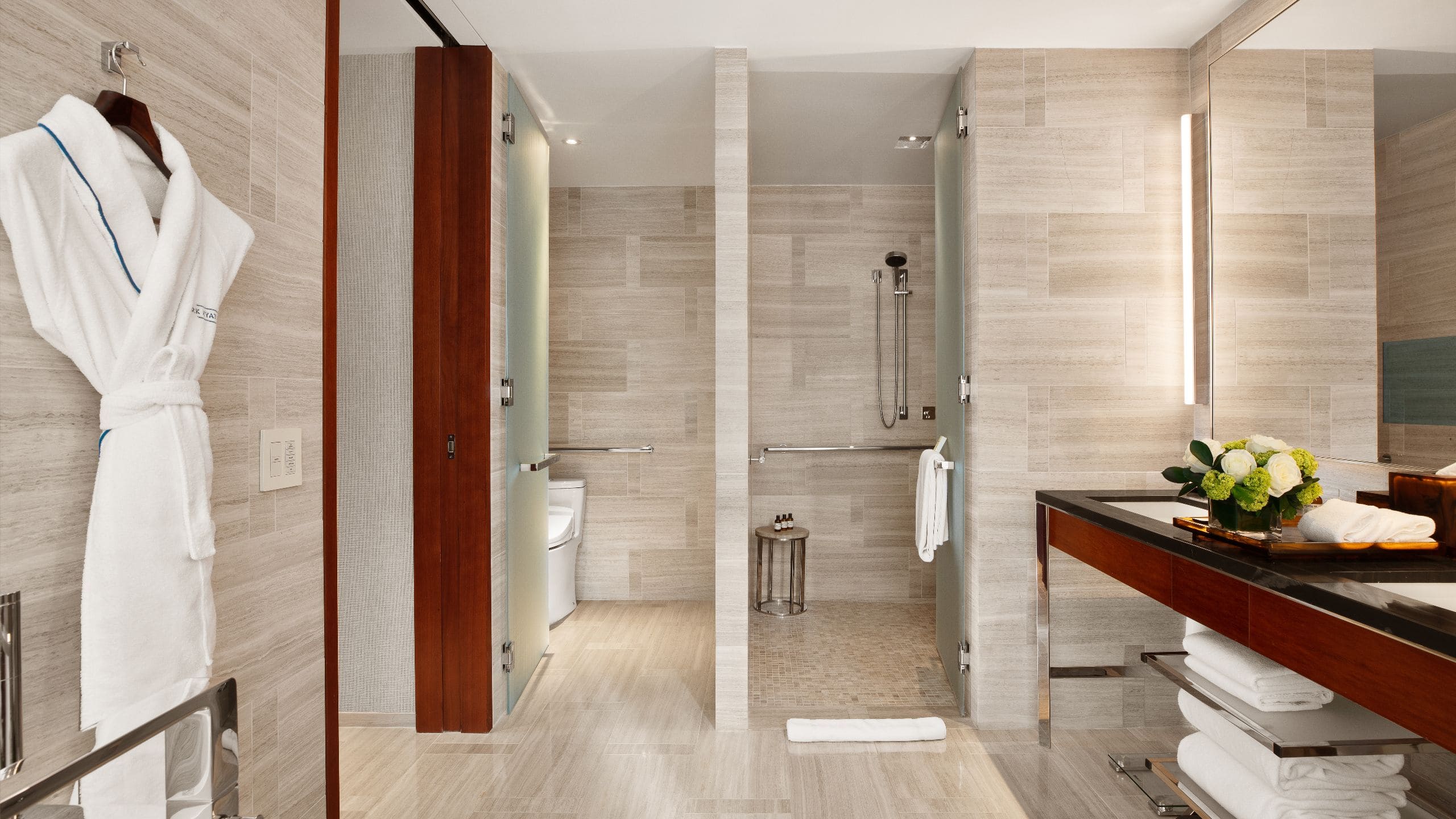 A spacious modern bathroom with accessibility features including grab bars and a roll in shower
