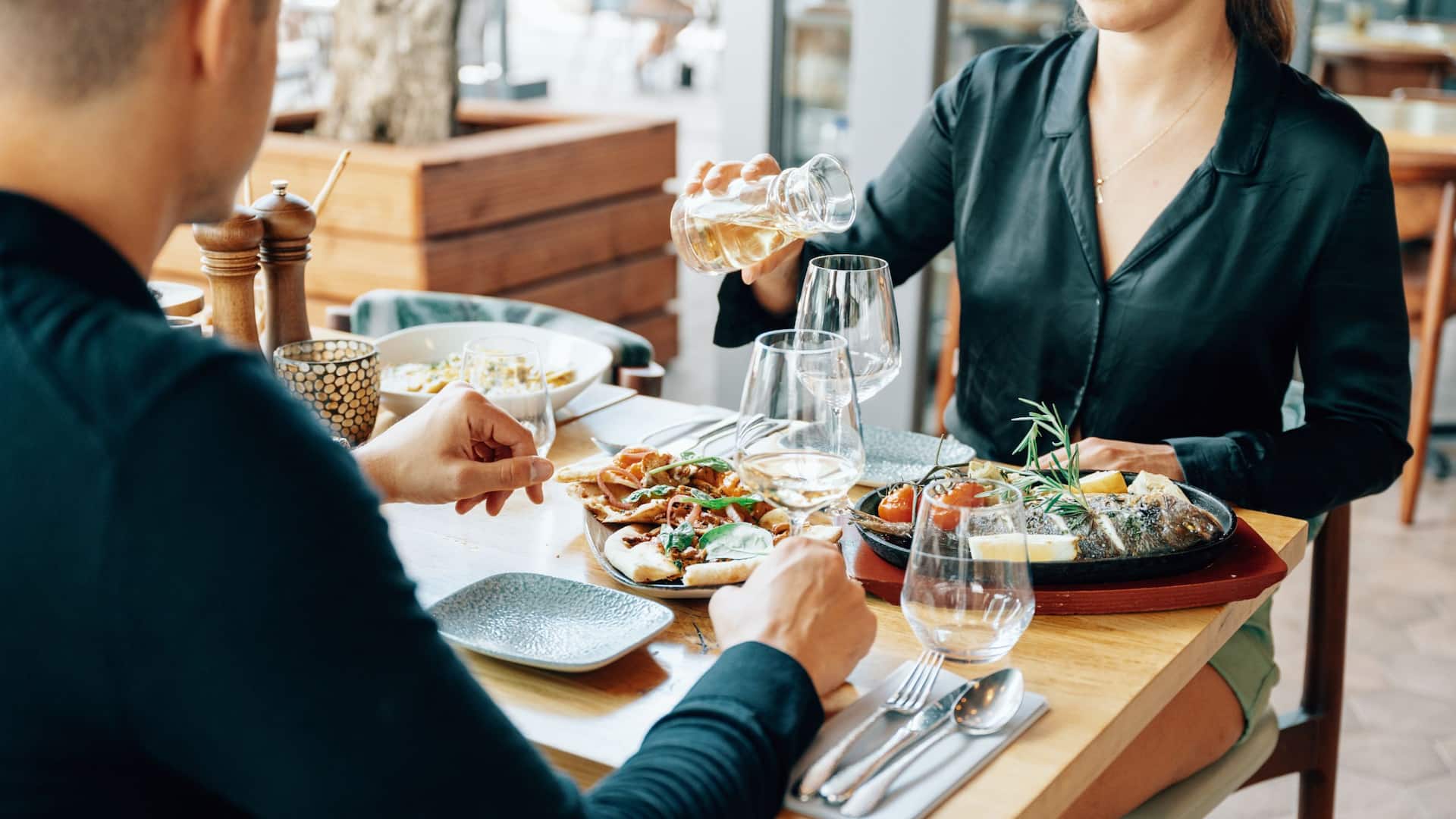 Man and woman toast each other at the set table at Grissini Restaurant of Hyatt Regency Cologne
