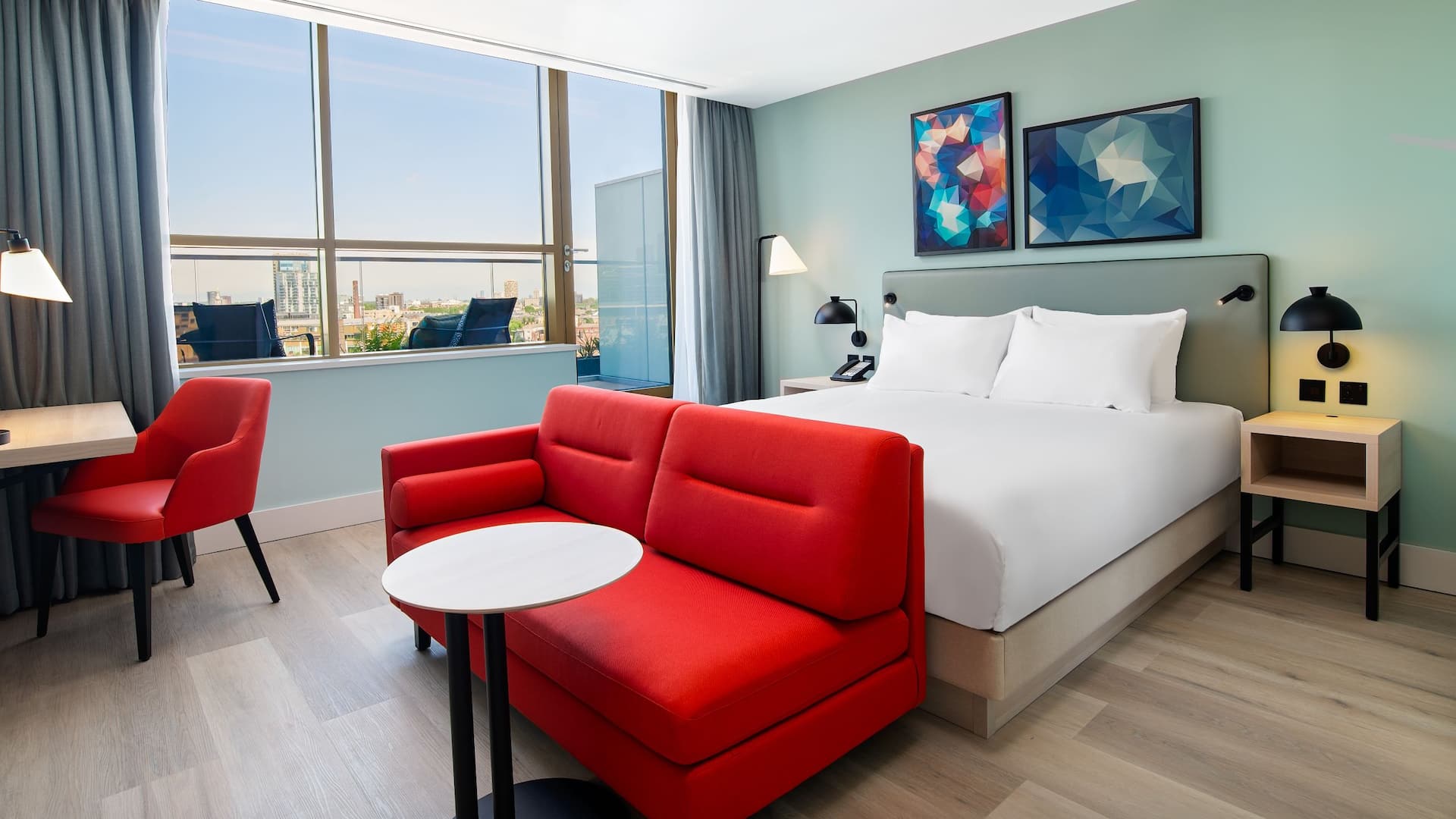 King bedroom at Hyatt Place London City east, with balcony, sofabed and city view.