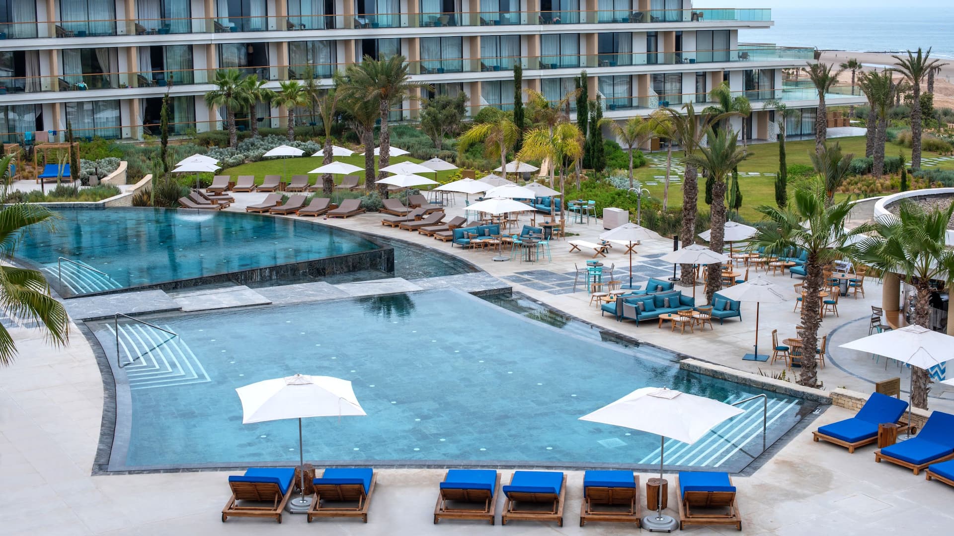 Hotel pool surrounded by lush greenery and lounge chairs, offering a relaxing  spot for guests to unwind.