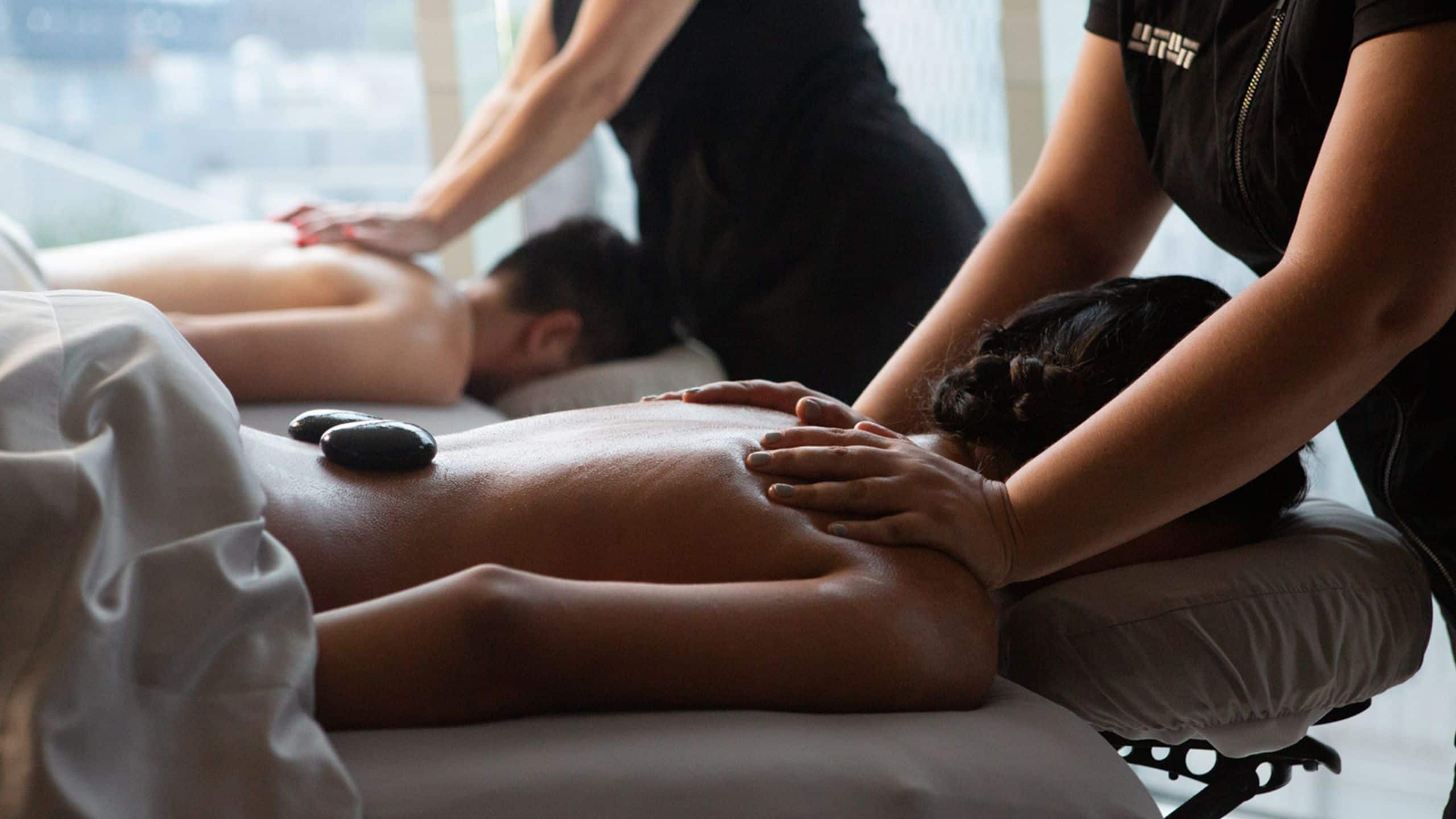 Two guests receiving massages with hot stones in the spa