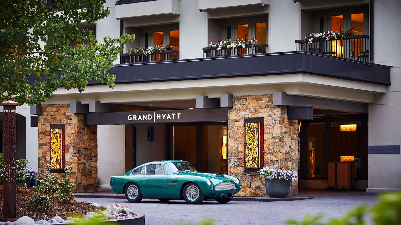 Entrance to hotel with teal colored car in driveway