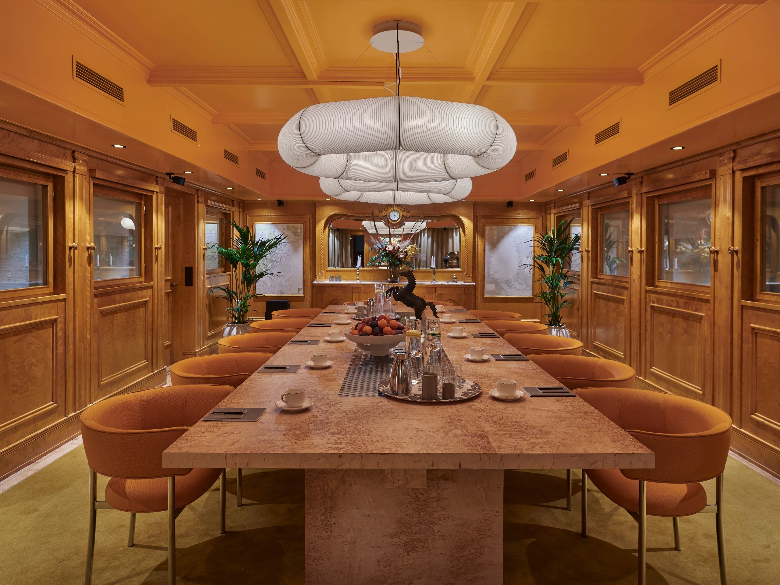 a conference room dressed in wooden panels and a large mirror in one end, a conference table with ten chairs.