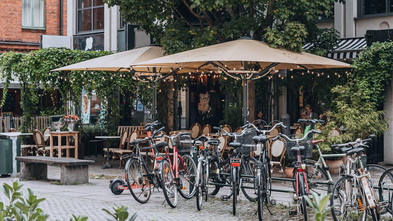 A bunch of bicycles parked outside of a Coffee shop in Malmö city center 
