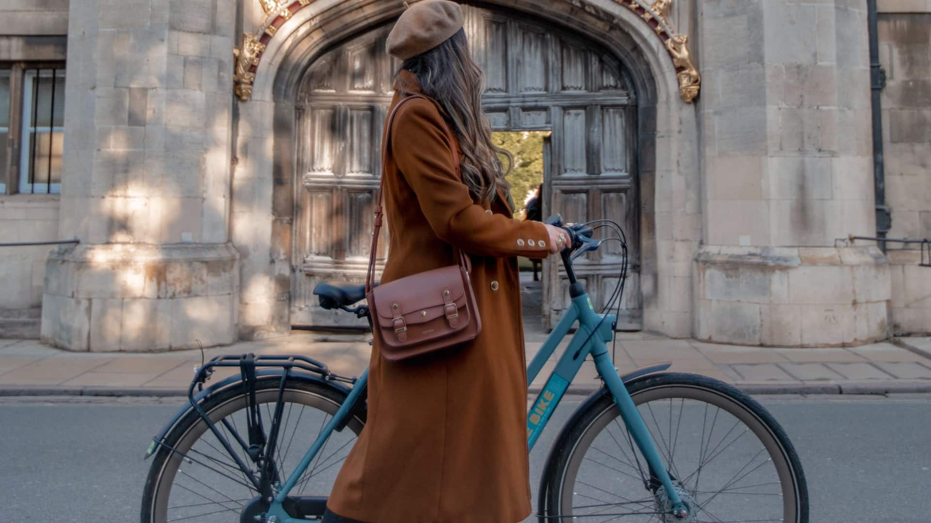 Woman holding a bicycle in front of Cambridge cathedral