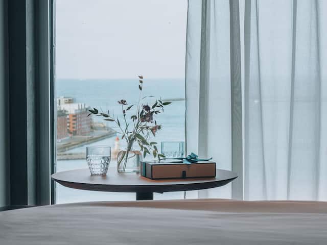 Blommor och ett par vattenglas på ett bord i ett King Bed Room med havsutsikt och Malmö Hamn i bakgrunden 