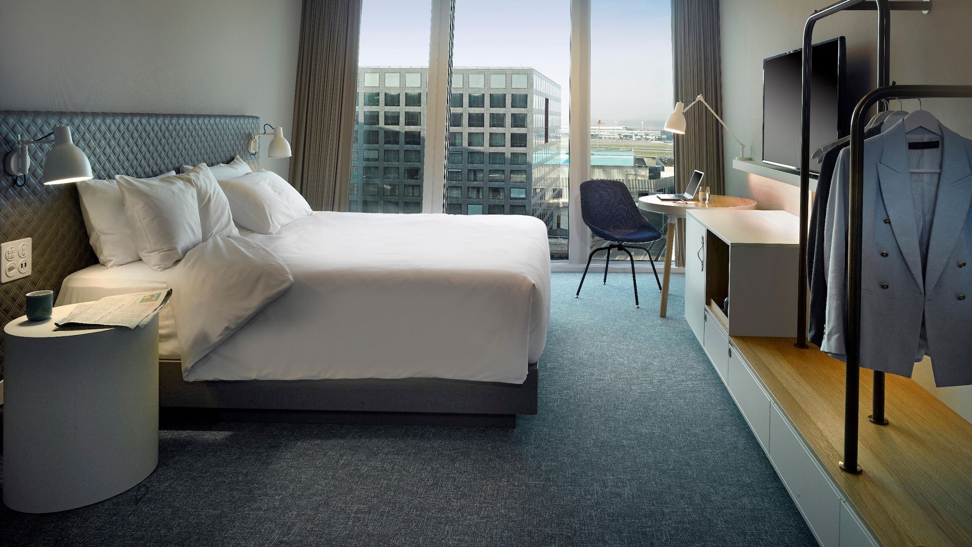 A king bed hotel room on a high floor, floor-to-ceiling windows, a work-desk and a beautiful view overlooking Zurich airport.