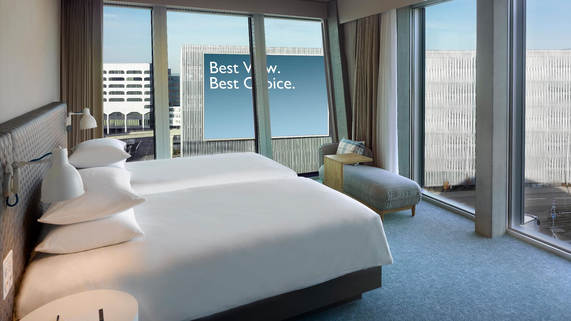 This two twin bed hotel room in Zurich is located on a high floor, offers floor-to-ceiling windows, a cosy corner sofa and offers a stunning view of Zurich airport.