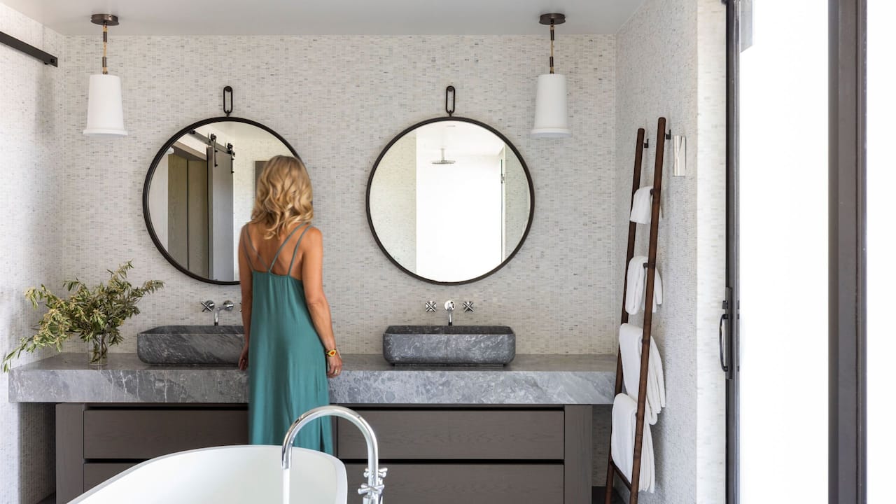 Woman getting ready in suite bathroom with double sinks