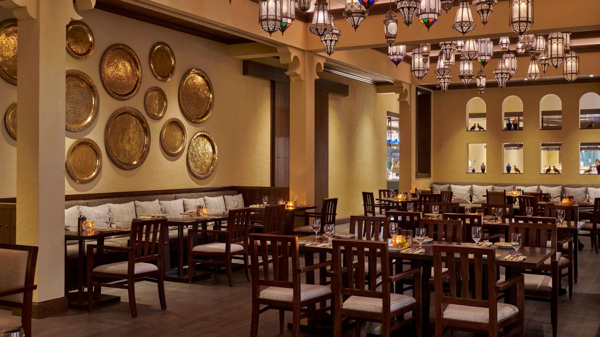 1 of 1 Asmahan at Grand Hyatt Al Khobar an elegant Levantine restaurant featuring warm ambient lighting, intricate hanging lanterns, and traditional gold plated wall decor, The inviting dining space is adorned with wooden furniture