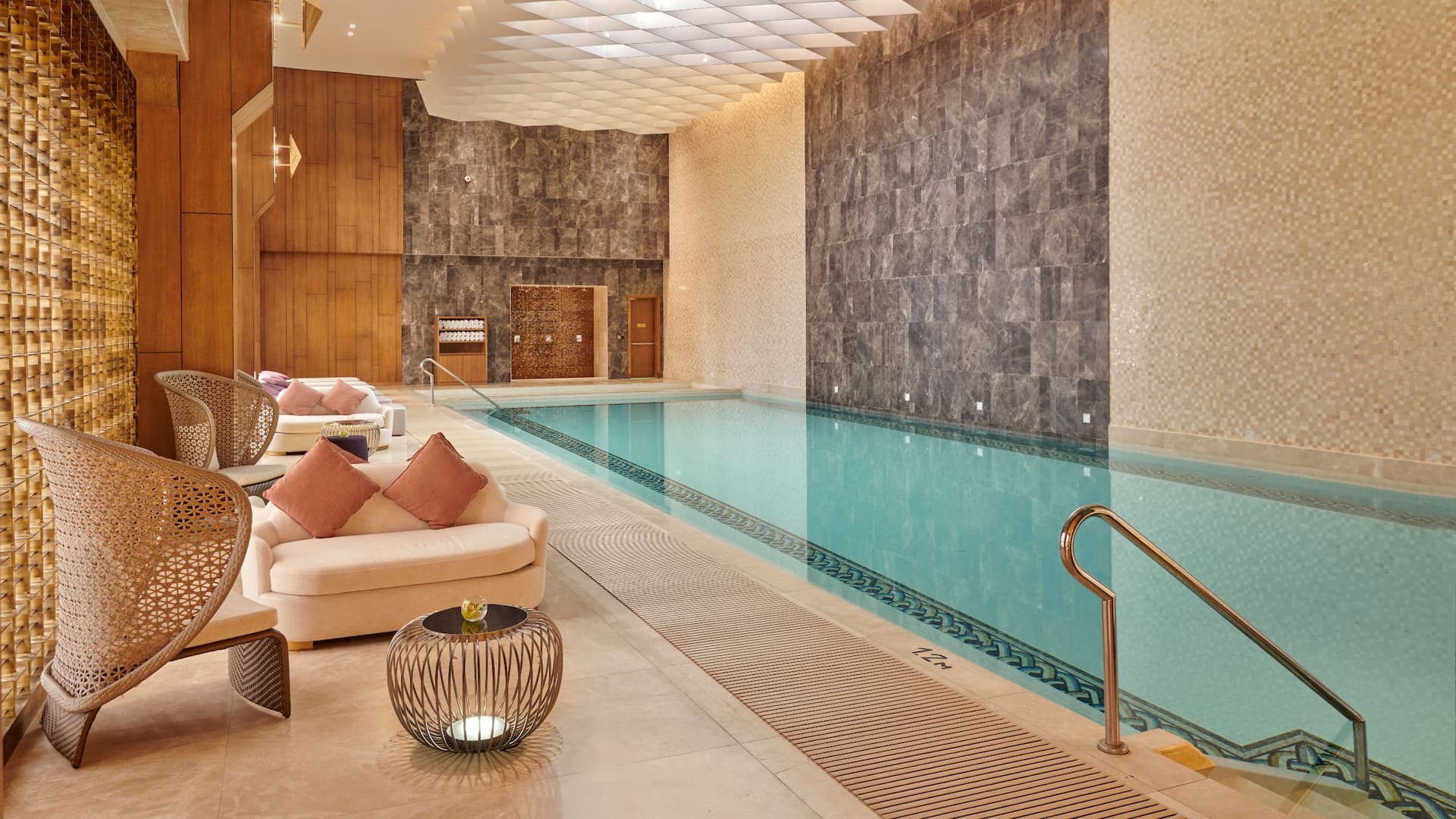 Elegant indoor swimming pool at Grand Hyatt Al Khobar, featuring luxurious lounge seating, warm lighting, and sophisticated decor for a relaxing experience