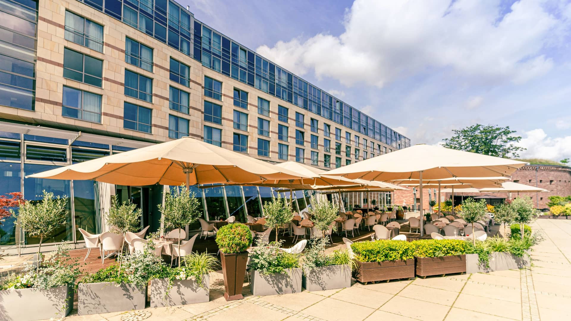 Terrace of the Bellpepper Restaurant with open parasols on the Rhine piazza during sunny day