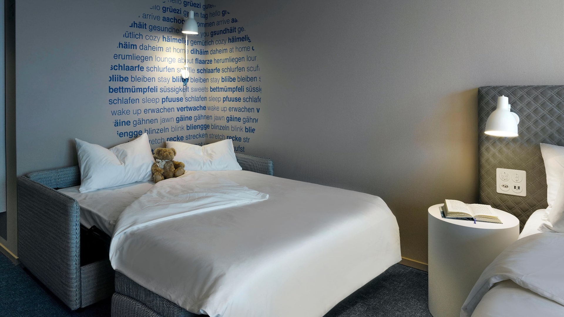 Modern hotel room in a Swiss design, with a king bed and a large sofa bed suitable for children, located at Zurich Airport.