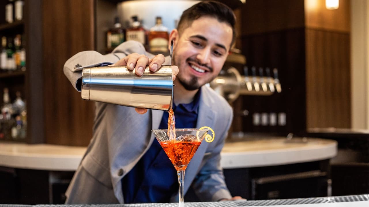 Bartender pouring an orange specialty drink